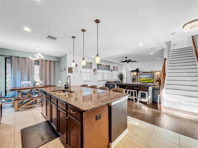 kitchen with decorative light fixtures, sink, an island with sink, light wood-type flooring, and ceiling fan