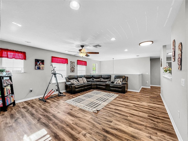 living room with visible vents, ceiling fan, baseboards, and wood finished floors