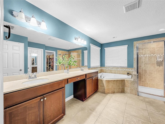 bathroom featuring a textured ceiling, tile patterned flooring, shower with separate bathtub, and dual bowl vanity