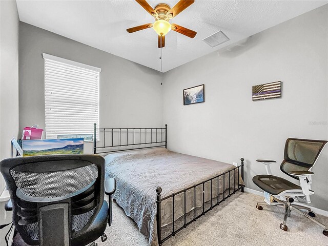 bedroom with a textured ceiling, ceiling fan, and light carpet