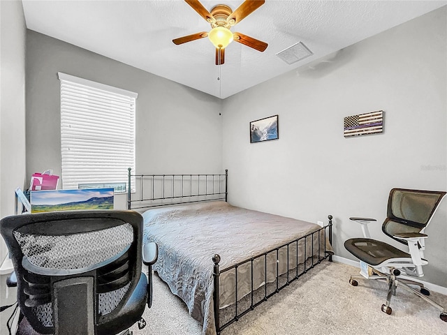 bedroom featuring visible vents, baseboards, light colored carpet, ceiling fan, and a textured ceiling