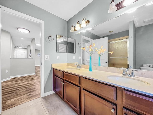 full bathroom featuring a stall shower, double vanity, a sink, and tile patterned floors