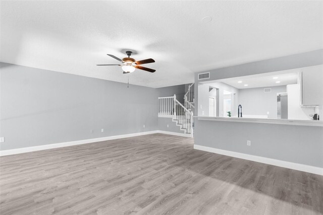 unfurnished living room featuring light hardwood / wood-style flooring and ceiling fan