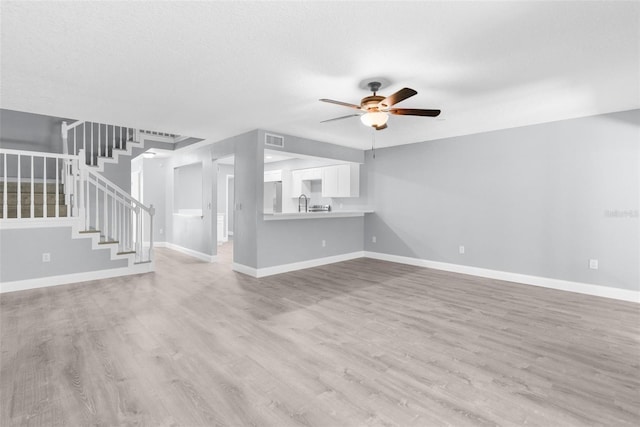 unfurnished living room with a textured ceiling, light hardwood / wood-style flooring, and ceiling fan