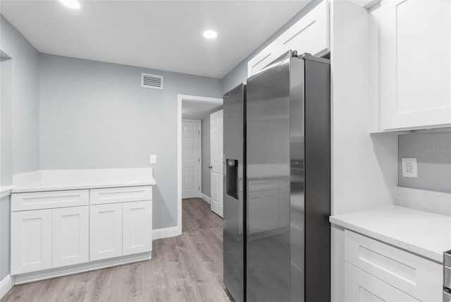 kitchen with light stone counters, light hardwood / wood-style floors, stainless steel fridge with ice dispenser, and white cabinets