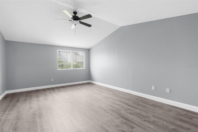 empty room with ceiling fan, lofted ceiling, and wood-type flooring