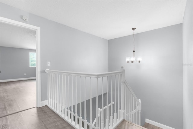 stairway featuring a textured ceiling, an inviting chandelier, and hardwood / wood-style floors