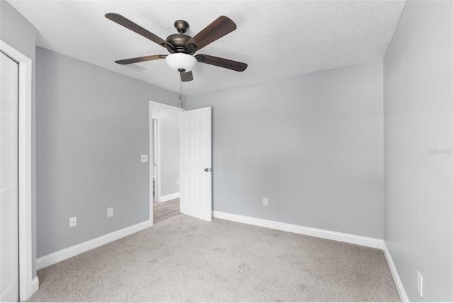 carpeted spare room featuring ceiling fan and a textured ceiling