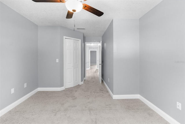 empty room with ceiling fan, a textured ceiling, and carpet flooring