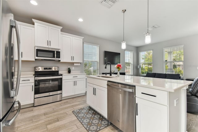 kitchen with a wealth of natural light, an island with sink, appliances with stainless steel finishes, and white cabinetry