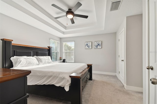 bedroom featuring a raised ceiling, light colored carpet, and ceiling fan