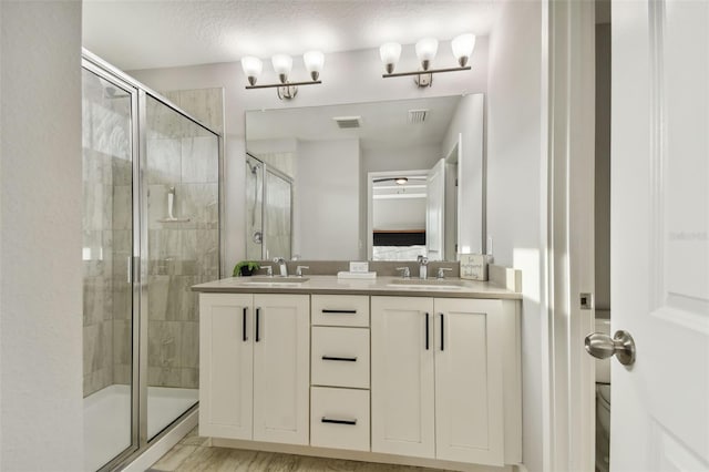 bathroom featuring a textured ceiling, vanity, a shower with shower door, hardwood / wood-style floors, and toilet