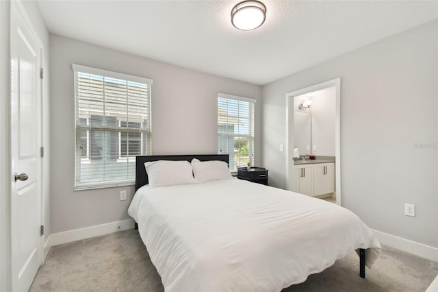 bedroom featuring light colored carpet and connected bathroom