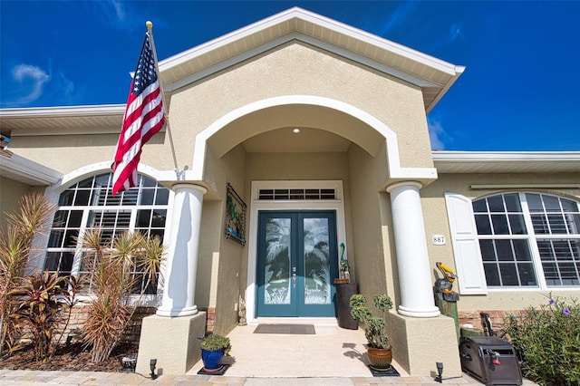 view of exterior entry featuring french doors and stucco siding