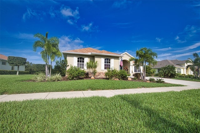 view of front of house with concrete driveway, a front lawn, and stucco siding