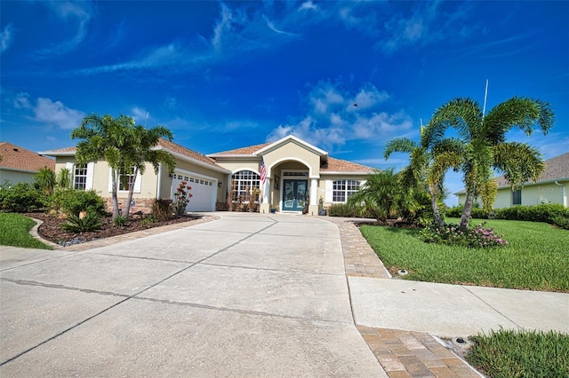 mediterranean / spanish home featuring french doors, stucco siding, concrete driveway, an attached garage, and a front lawn