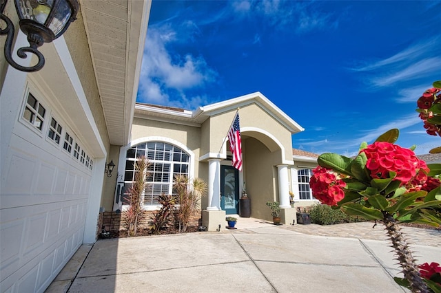 doorway to property featuring driveway, an attached garage, and stucco siding