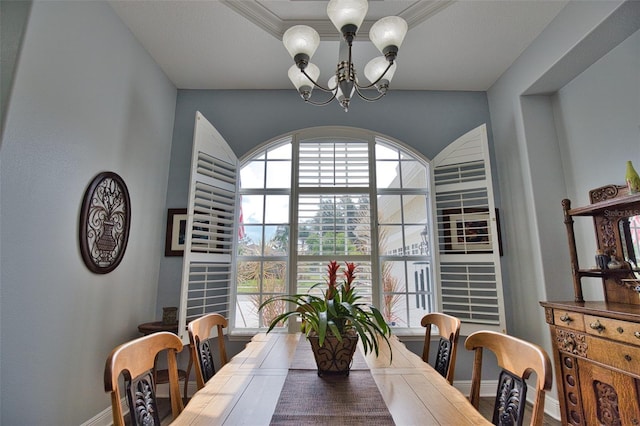 dining area featuring baseboards, ornamental molding, a raised ceiling, and an inviting chandelier