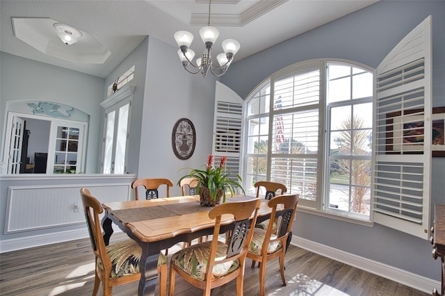 dining area featuring crown molding, wood finished floors, a raised ceiling, and an inviting chandelier