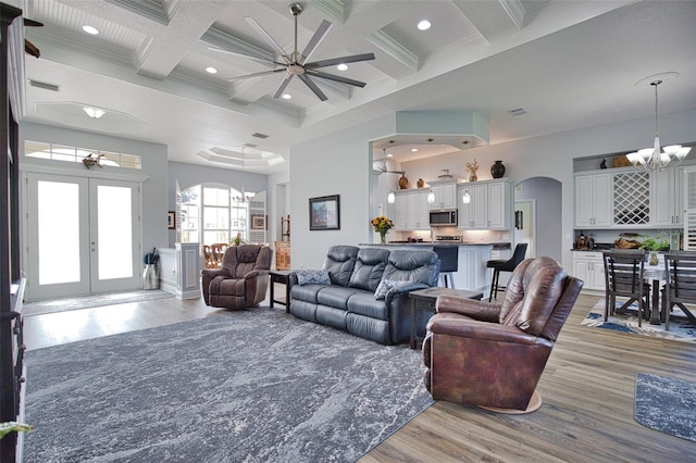 living area featuring arched walkways, beam ceiling, recessed lighting, a high ceiling, and coffered ceiling