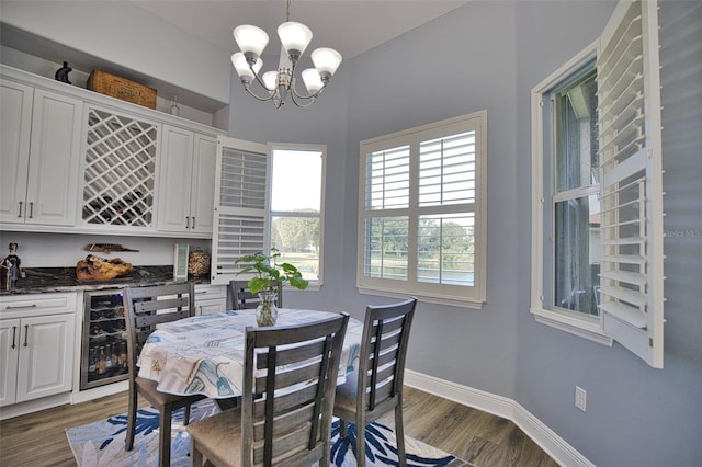 dining area featuring a notable chandelier, a dry bar, dark wood finished floors, and baseboards