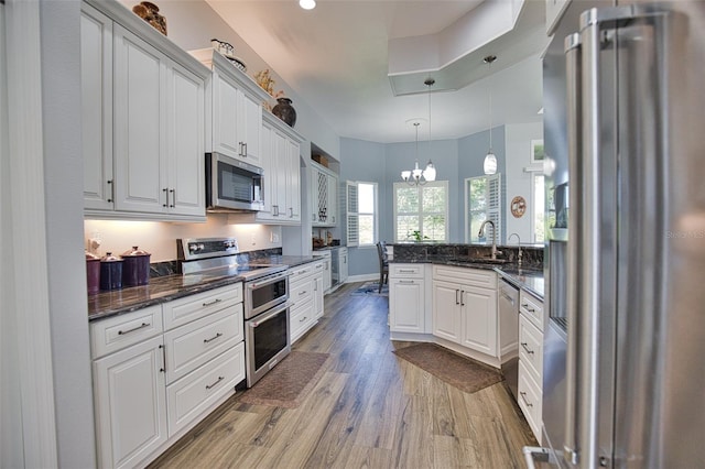 kitchen featuring white cabinets, light wood-style flooring, a peninsula, and stainless steel appliances