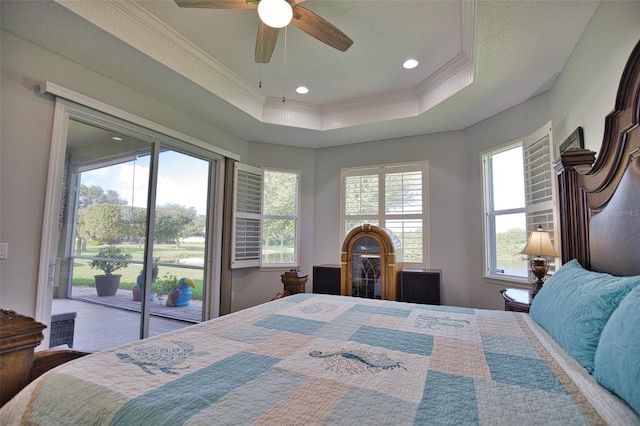 bedroom with access to outside, a tray ceiling, multiple windows, and crown molding