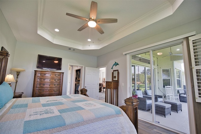 bedroom featuring visible vents, ornamental molding, wood finished floors, access to exterior, and a tray ceiling