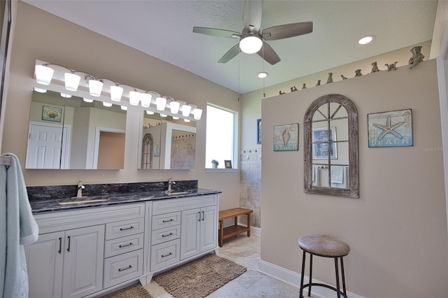 bathroom featuring double vanity, a sink, baseboards, and a walk in shower