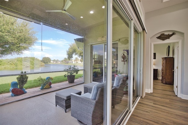 sunroom / solarium with a water view and ceiling fan