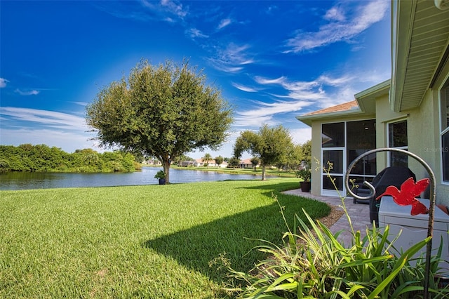 view of yard featuring a sunroom and a water view