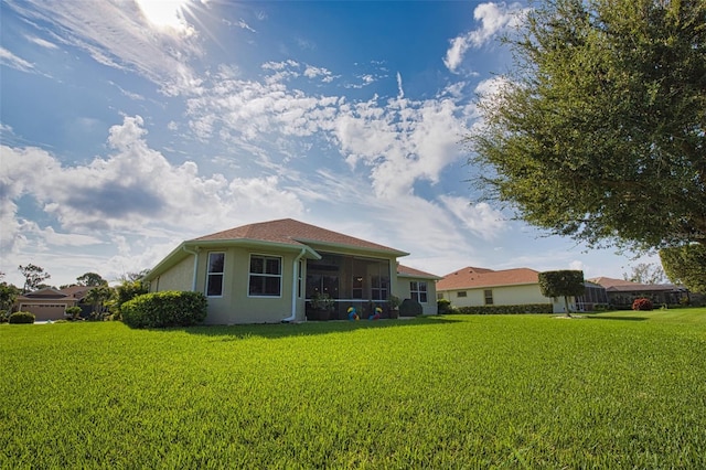 rear view of property with a sunroom, stucco siding, and a yard