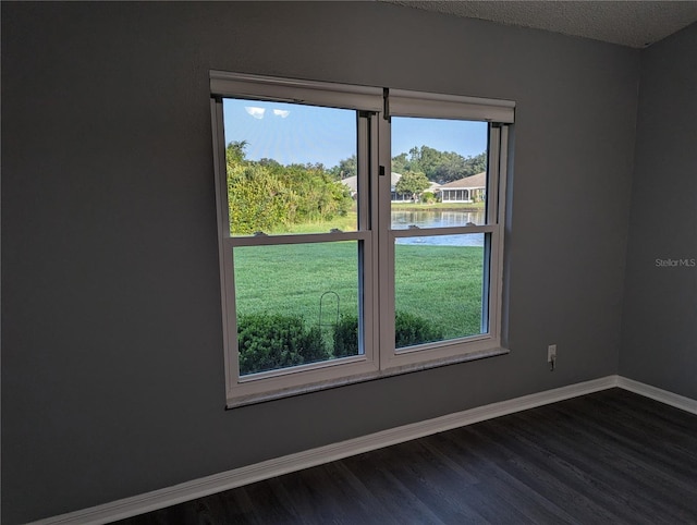 empty room with wood-type flooring, a textured ceiling, a water view, and plenty of natural light