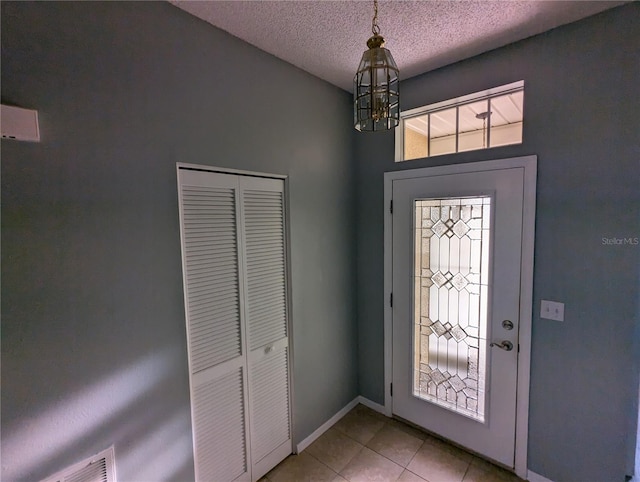 tiled entrance foyer featuring a textured ceiling and an inviting chandelier