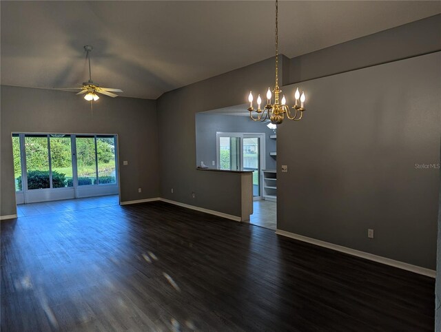 spare room featuring ceiling fan with notable chandelier, vaulted ceiling, and dark wood-type flooring