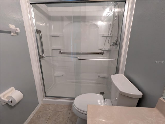 bathroom featuring tile patterned floors, toilet, and a shower with door