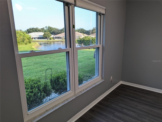 empty room with dark hardwood / wood-style floors and a water view