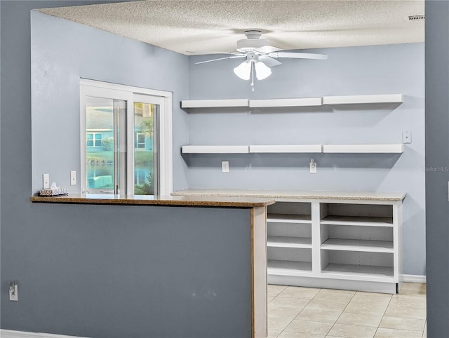 kitchen featuring ceiling fan, light tile patterned floors, and a textured ceiling