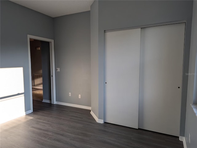 unfurnished bedroom featuring dark hardwood / wood-style flooring and a closet