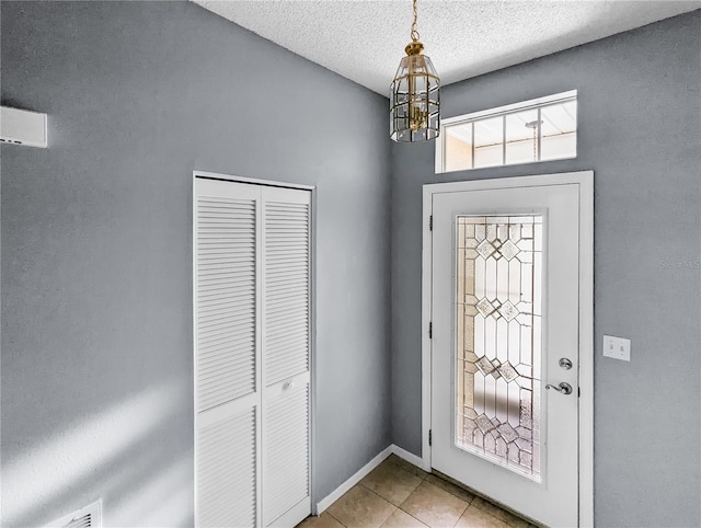 entrance foyer with light tile patterned floors, a textured ceiling, and an inviting chandelier