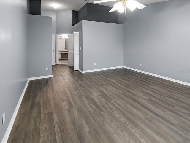 unfurnished living room with a towering ceiling, dark hardwood / wood-style flooring, and ceiling fan