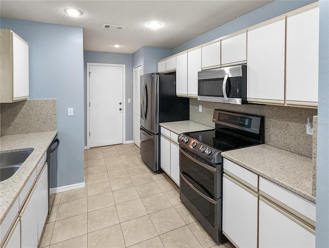 kitchen featuring white cabinetry, stainless steel appliances, backsplash, a textured ceiling, and light tile patterned floors