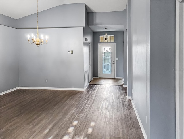 foyer entrance with dark wood-type flooring, high vaulted ceiling, and a chandelier