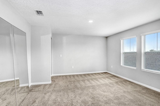 empty room featuring a textured ceiling and light colored carpet