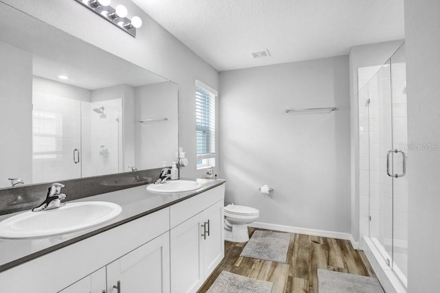 bathroom featuring vanity, toilet, hardwood / wood-style flooring, and a shower with shower door