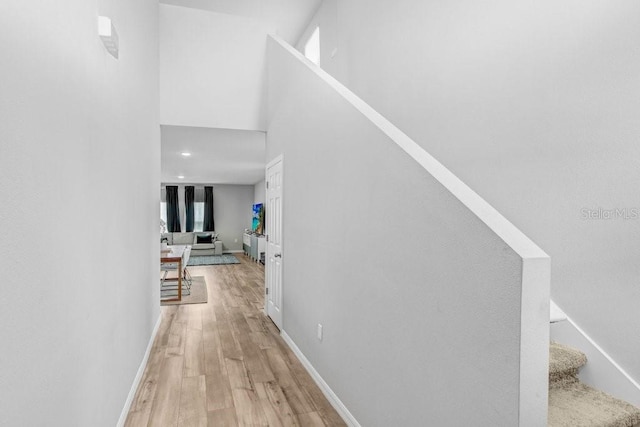 hallway with light hardwood / wood-style floors and a towering ceiling