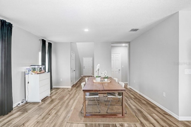 dining space with light hardwood / wood-style flooring and a textured ceiling