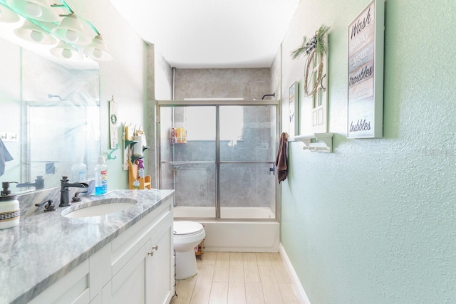 full bath featuring toilet, bath / shower combo with glass door, vanity, and baseboards