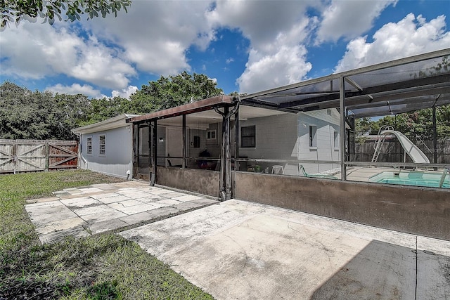 rear view of house with a patio, a fenced in pool, and a sunroom