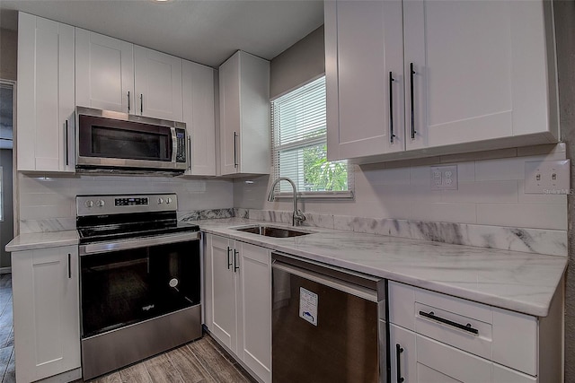 kitchen with sink, appliances with stainless steel finishes, light wood-type flooring, and white cabinetry